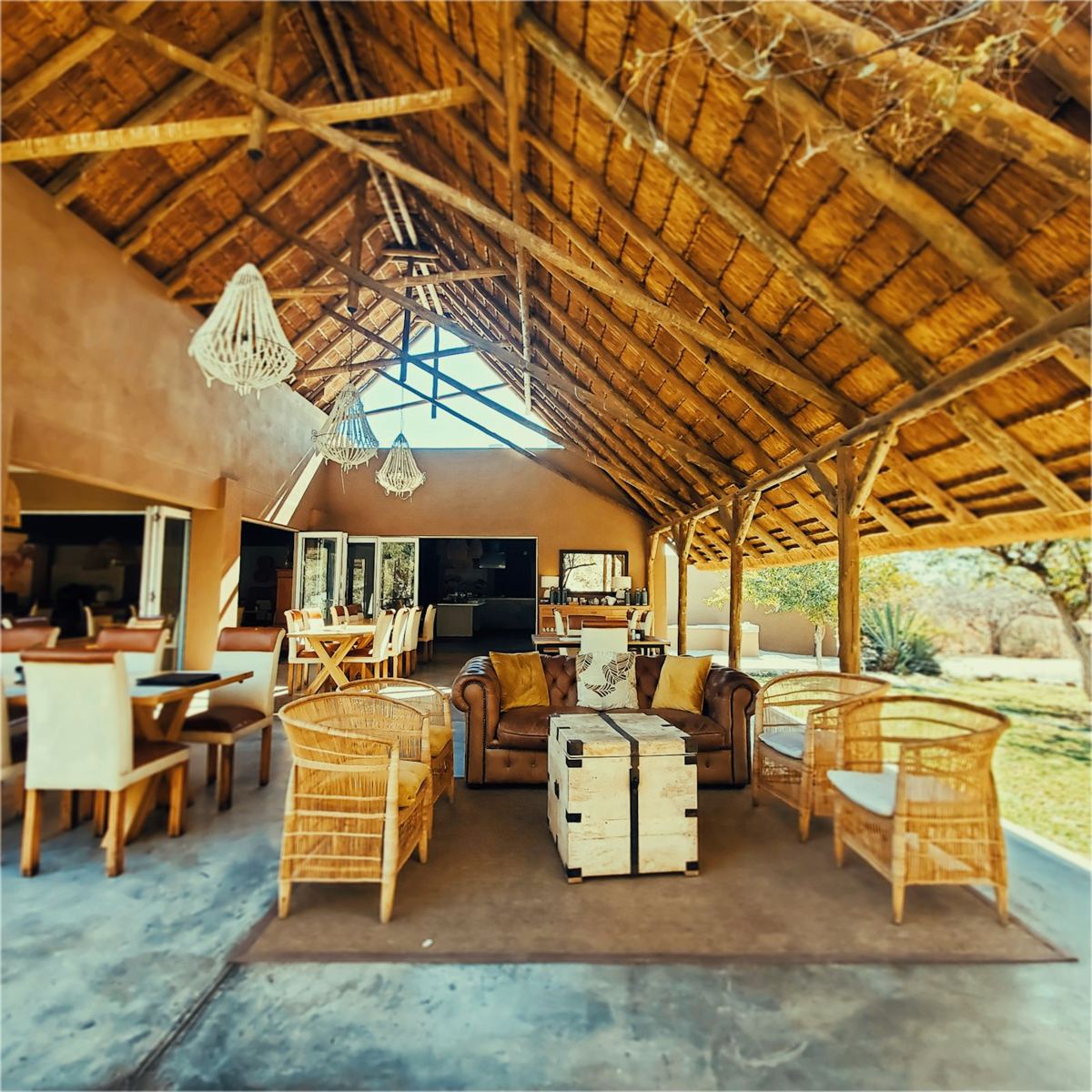 Open-air lodge lounge and dining area under a thatched roof