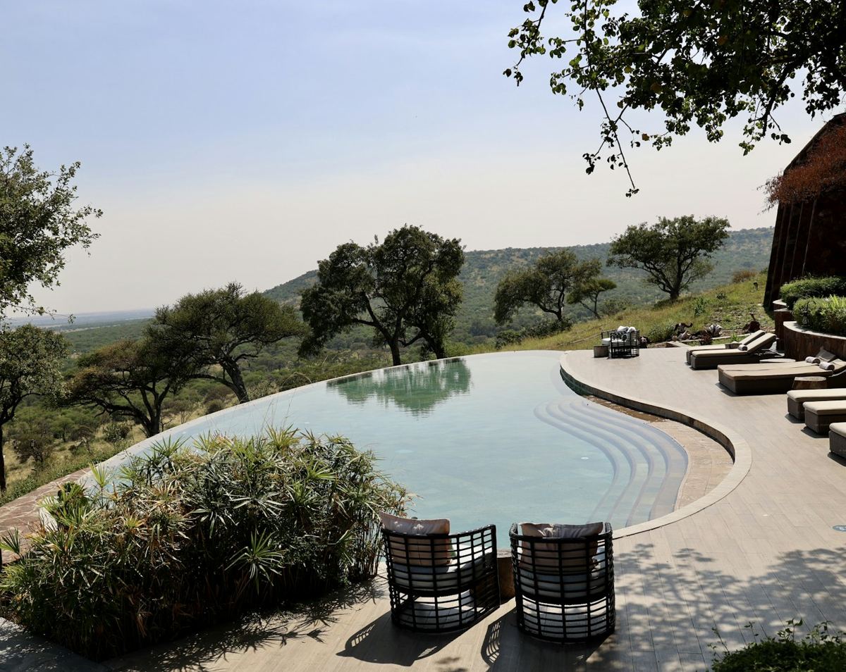 Infinity pool with loungers overlooking a green valley