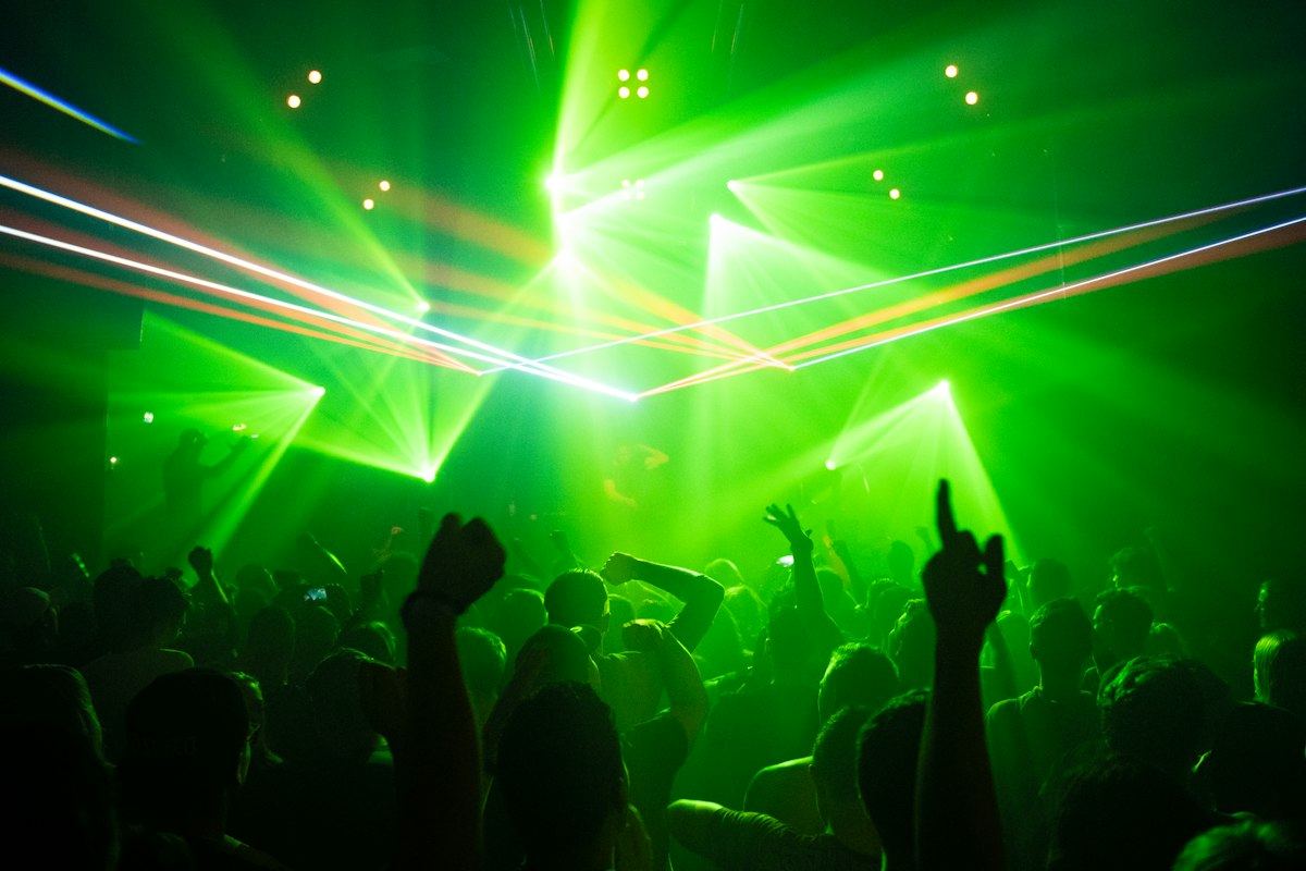 Crowd dancing under green club lights