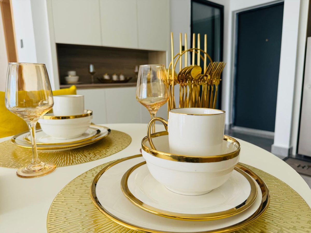 Dining table set with gold-rimmed plates, bowls, cups and glasses