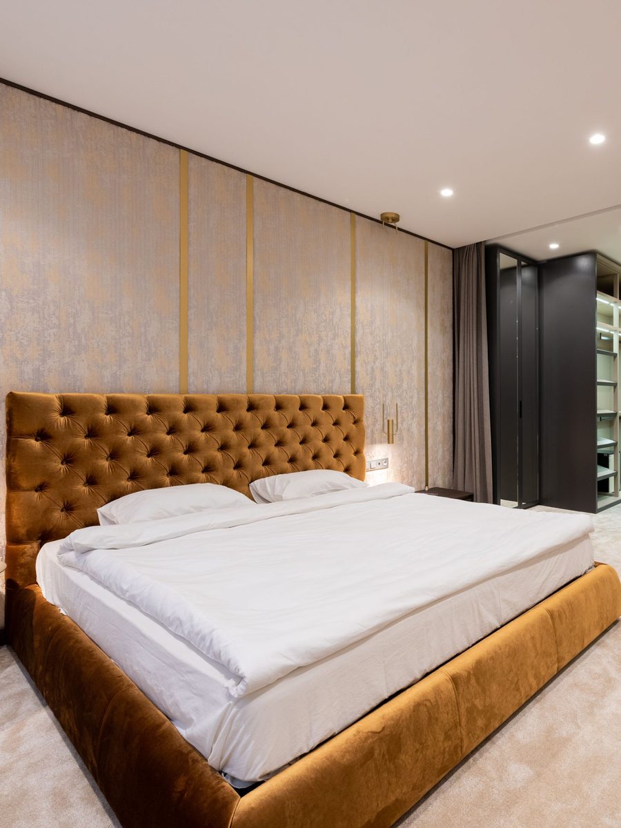 Bedroom with a tufted ochre headboard and crisp white bedding