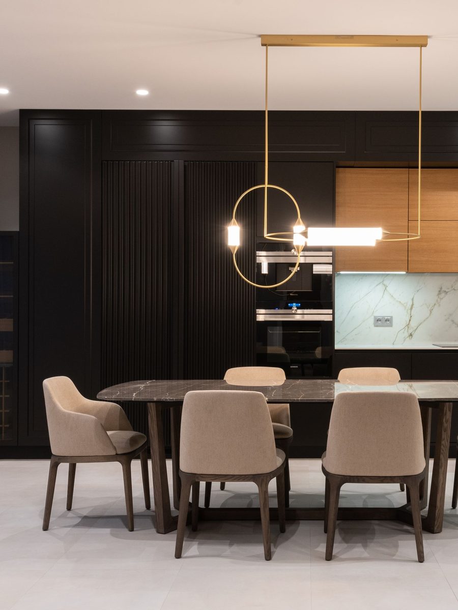 Dark kitchen with a gold pendant over a dining table and six chairs