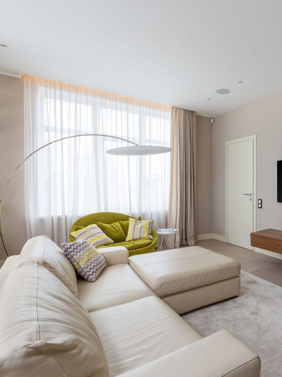Living room with a white L-shaped sofa, arc lamp and TV wall