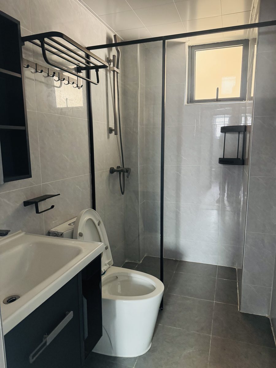 Bathroom with a glass shower, grey tiles and a dark vanity
