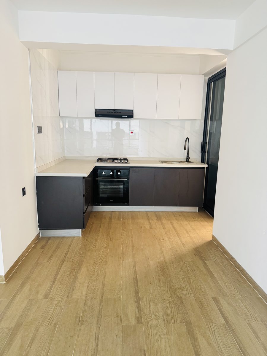 Empty fitted kitchen with white upper and dark lower cabinets